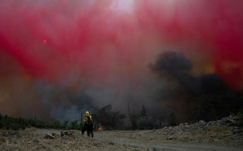A firefighter stands under a cloud of red fire retardant dropped by a plane on the Glass Fire in Deer Park, California, U.S. September 27, 2020. REUTERS/Adrees Latif TPX IMAGES OF THE DAY